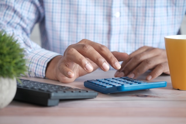 Close up of hands using a blue calculator